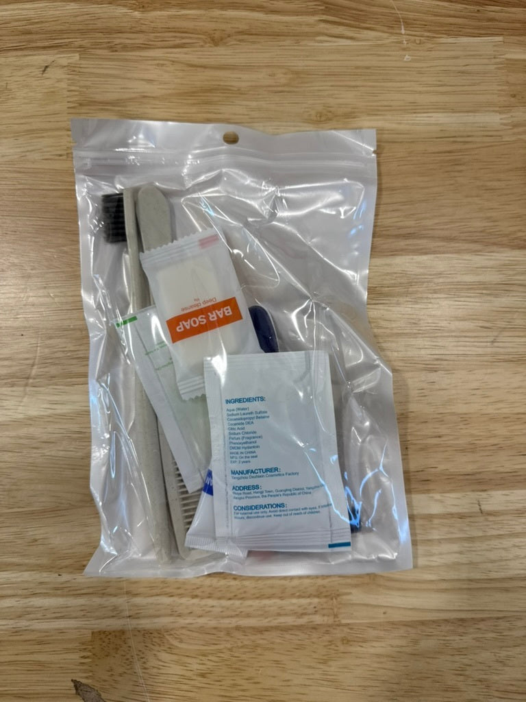 Packaged dental care items including a brush and packets on a wooden surface